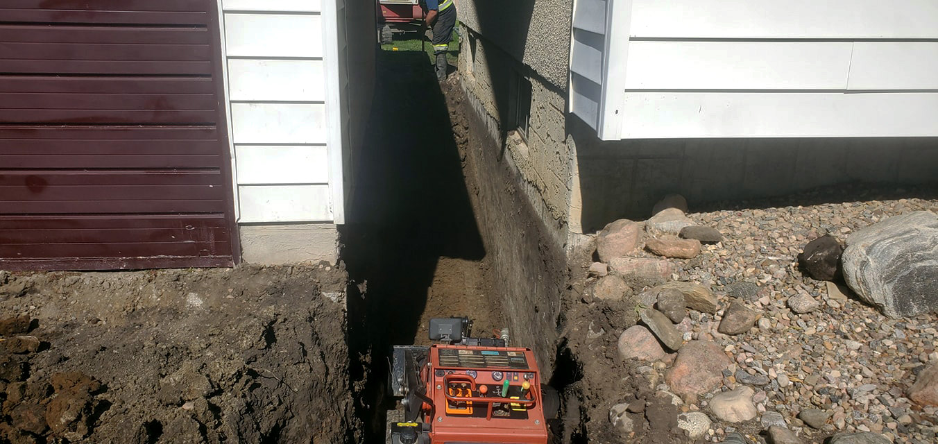 Trench dug between two houses to run sewer and water mains.